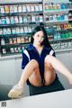 A woman sitting on top of a table in front of a vending machine.