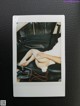 A polaroid photo of a woman sitting in a car.