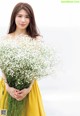 A woman in a yellow dress holding a bunch of flowers.