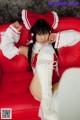 A woman in a red and white outfit sitting on a red couch.