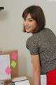 A woman standing in front of a desk with sticky notes on it.