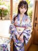 A woman in a blue kimono sitting on a window sill.