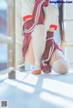 A woman in a red and white cheerleading uniform crouching on the ground.