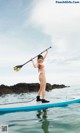 A woman in a bikini standing on a paddle board.