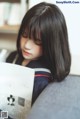 A woman sitting on a couch reading a book.