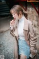 A woman in a white turtle neck sweater and a beige trench coat.