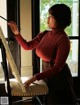 A woman in a red sweater is painting on a easel.