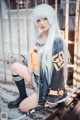 A woman with long white hair sitting on a wooden bench.